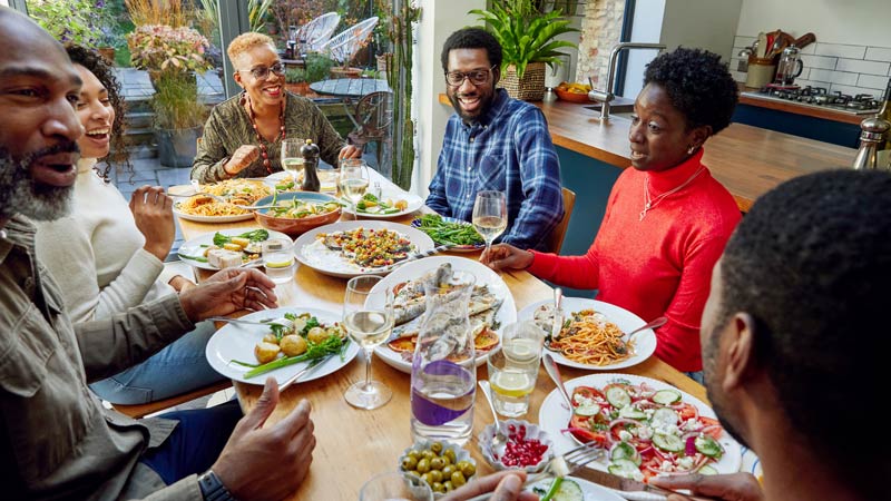 Friends and Family at a gathering eating at a table.