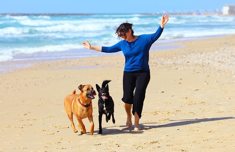happy woman and pets running on beach