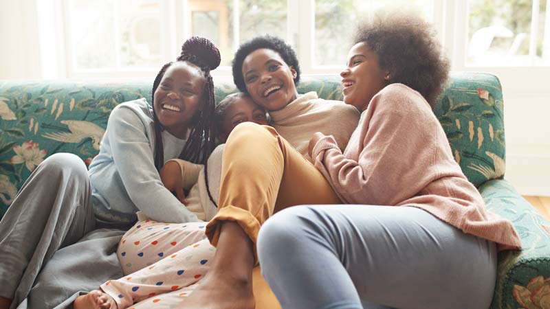 Retrato de una mujer feliz abrazando a sus hijas en casa
