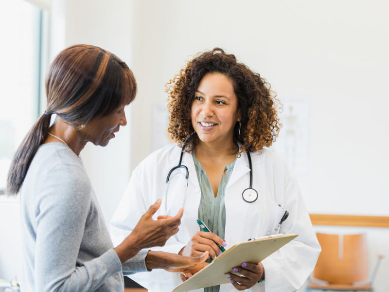 posed photo of female patient speaking with female doctor