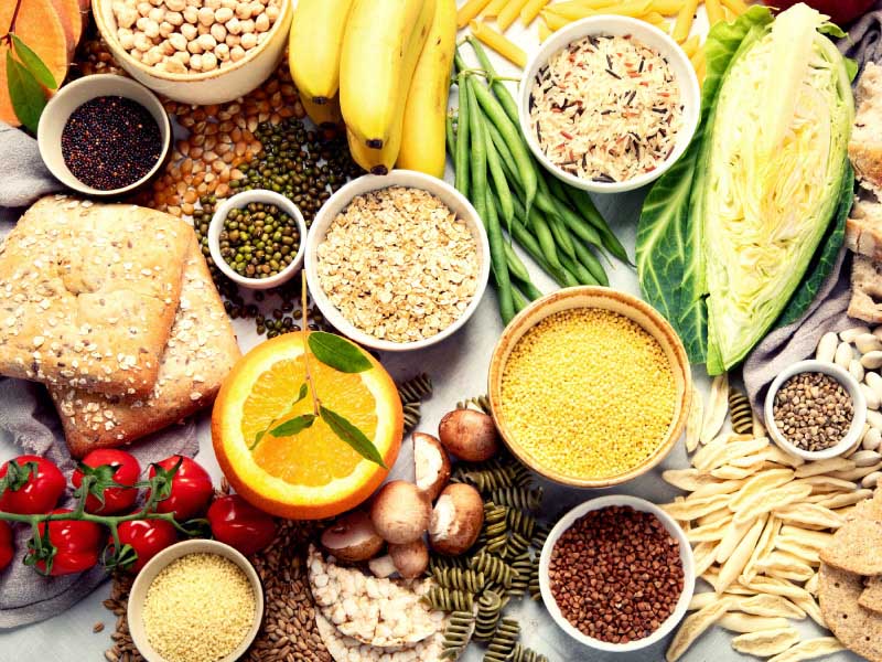 a wide variety of grains and carbs mixed with a few fruits and vegetables spread across a table top
