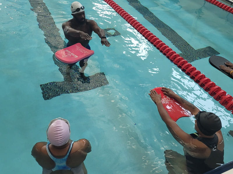 Brandon King (top), Tanika Smith (right) and Carmellia Jones (left) during a swim class at the West Charlotte High School pool in Charlotte, North Carolina. King learned to swim a few years ago and is now an instructor. (Photo courtesy of Nadine Ford)