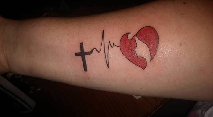 Christina Luntzer's left forearm showing her tattoo: a woman’s face inside a heart, connected to the squiggly lines of an EKG to represent a heartbeat, which is connected to a cross that represents her faith