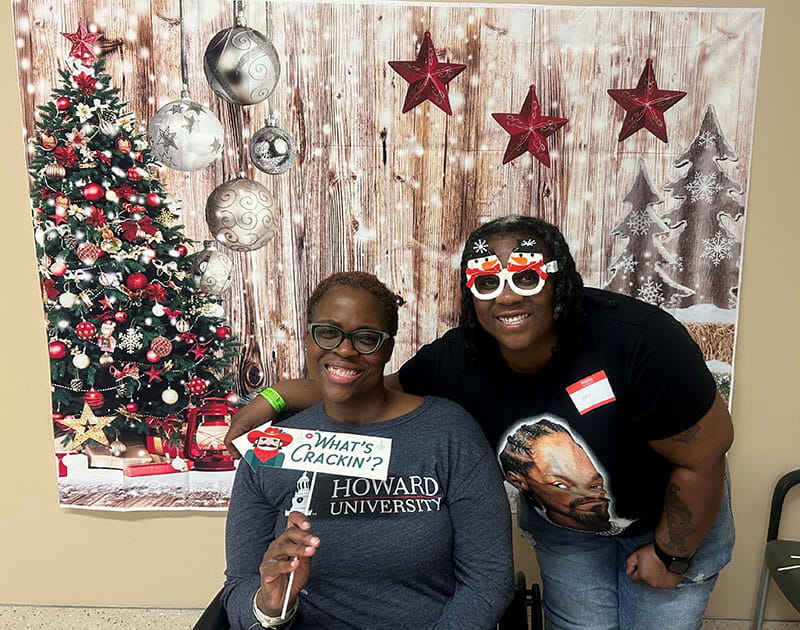 Kim Spight, left, and her daughter, Sharnay, posing together in front of a holiday backdrop
