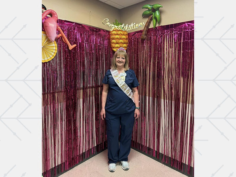 Natalie Daugherty wearing nursing scrubs, standing at a celebration for her retirement