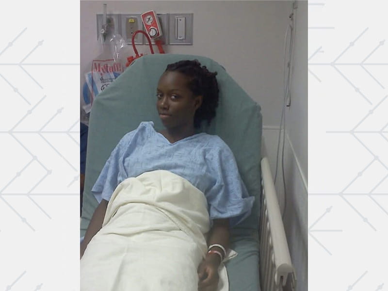 Post‑surgery photo of Whitney Johnson in a hospital bed, recovering well as her heart begins returning to a normal size.