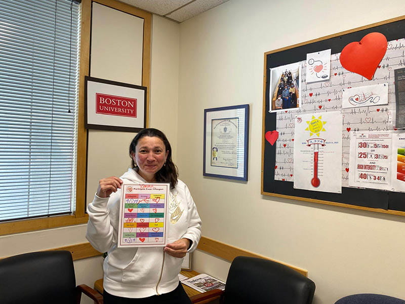 Ximena holds up her Participant Exam 4 Passport, showing hearts marking all 15 completed stations.