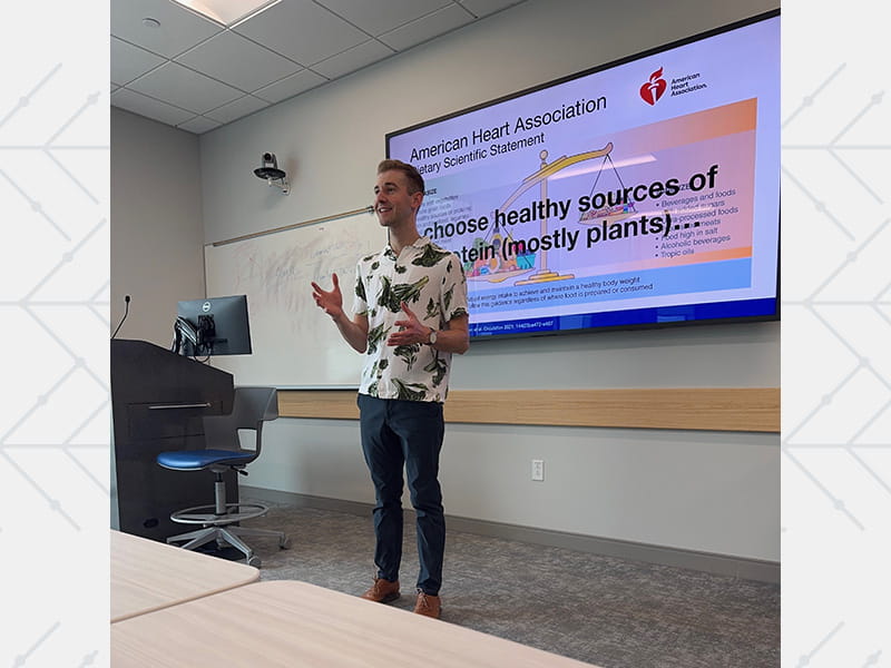 Dr. Matthew Landry standing at the front of a classroom and giving a presentation on nutrition