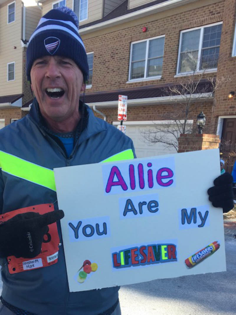 Mark Kleinschmidt at a race, holding a sign to thank his daughter Allison. (Photo courtesy of Mark Kleinschmidt)