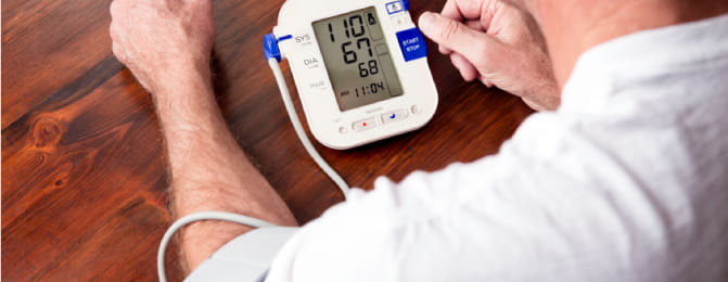 man taking his own blood pressure using an electronic blood pressure cuff