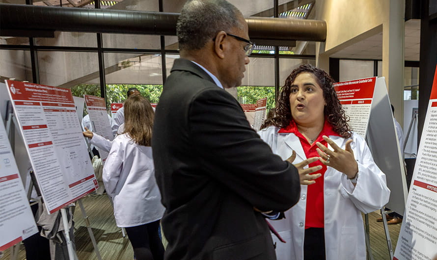 An American Heart Association Scholar is presenting her scientific poster to a program mentor.