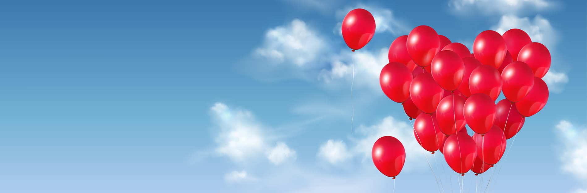 A cluster of red balloons forming the shape of a heart against a blue sky