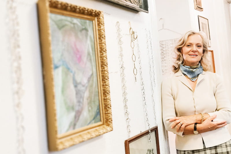 Older woman standing near framed artwork in gallery