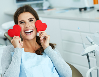 Smiling woman holding hearts by her teeth