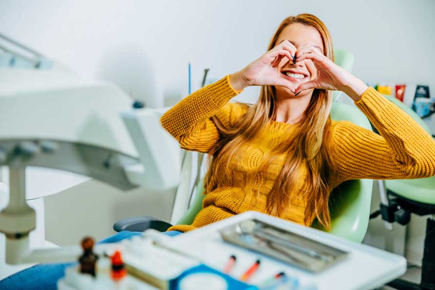 Woman making heart hands in dental chair