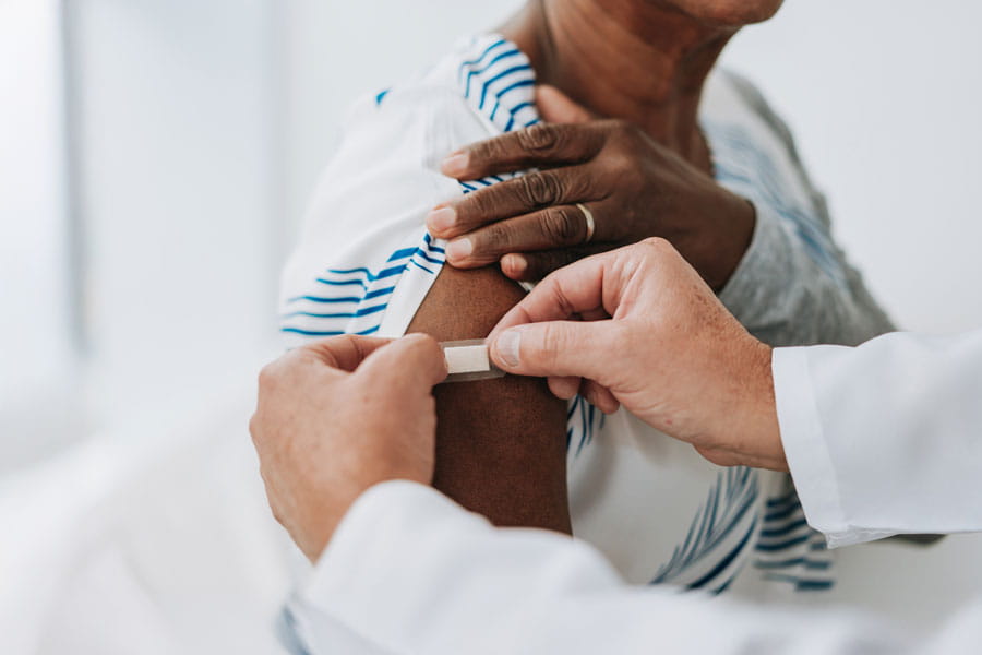 Woman having a bandage put on arm after a shot
