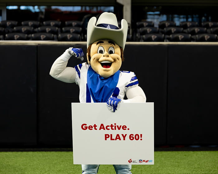 Rowdy, the Dallas Cowboys mascot, standing on the field holding a sign that says "Get Active. PLAY 60!"