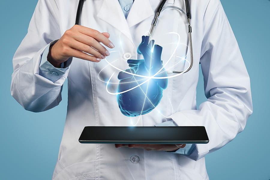 Close-up of a doctor's hands holding a tablet with an illustration of an anatomical heart floating above the screen