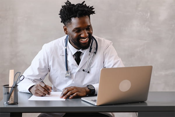 Health care professional smiling while working on his laptop