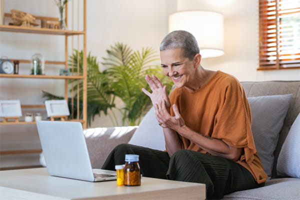Woman smiling and sitting on her couch while looking at her laptop