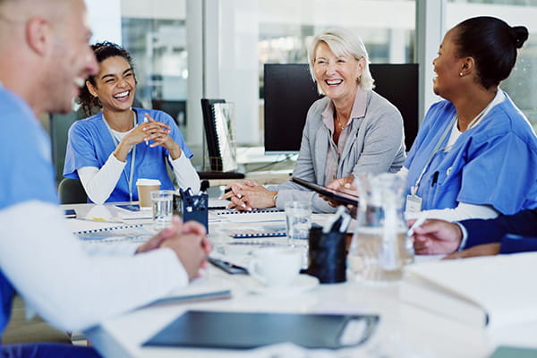 Group of medical professionals sitting around a table and smiling