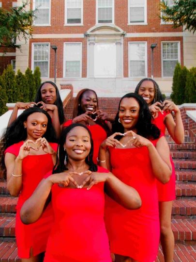 Women dressed in red making a heart shape with their hands