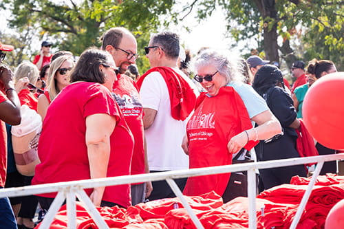 A group of volunteers smile as they proudly pick up their event t-shirts at AHA Heartwalk 2024 in Chicago