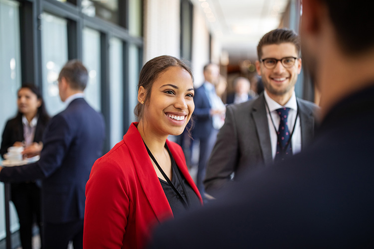 Business professionals talking while standing in a convention center corridor during coffee break.