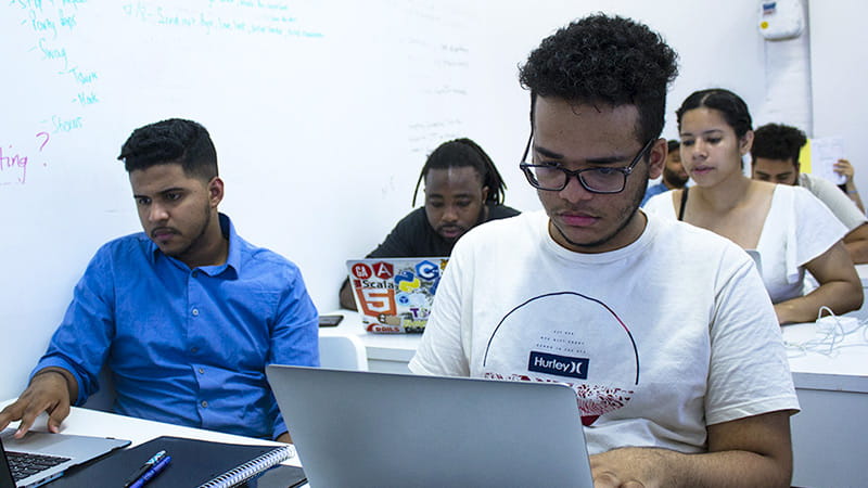 A classroom of diverse students working on laptop computers at The Knowledge House