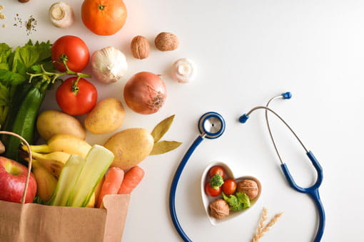 grocery bag of fruits and vegetables on a table next to a stethoscope