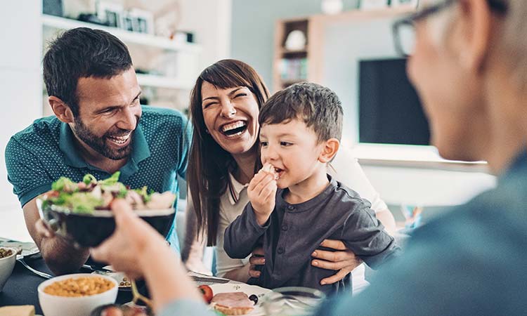 Una familia riendo y cenando juntos.