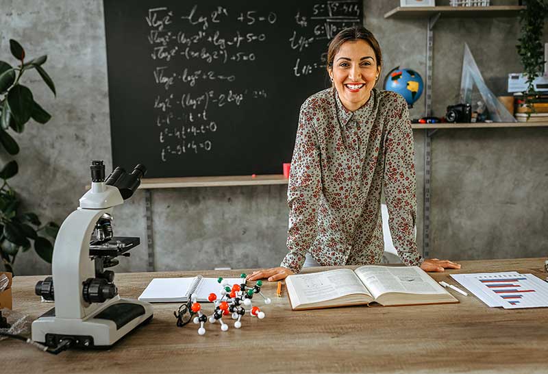 teacher standing behind desk