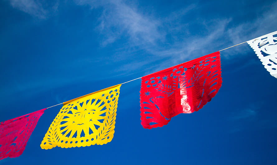 A bright string of fiesta flags against a blue sky