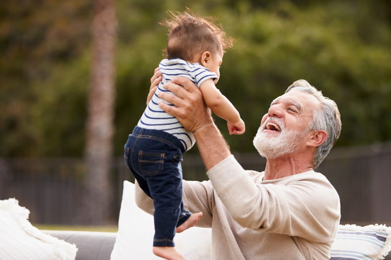 smiling grandpa playing with toddler outside