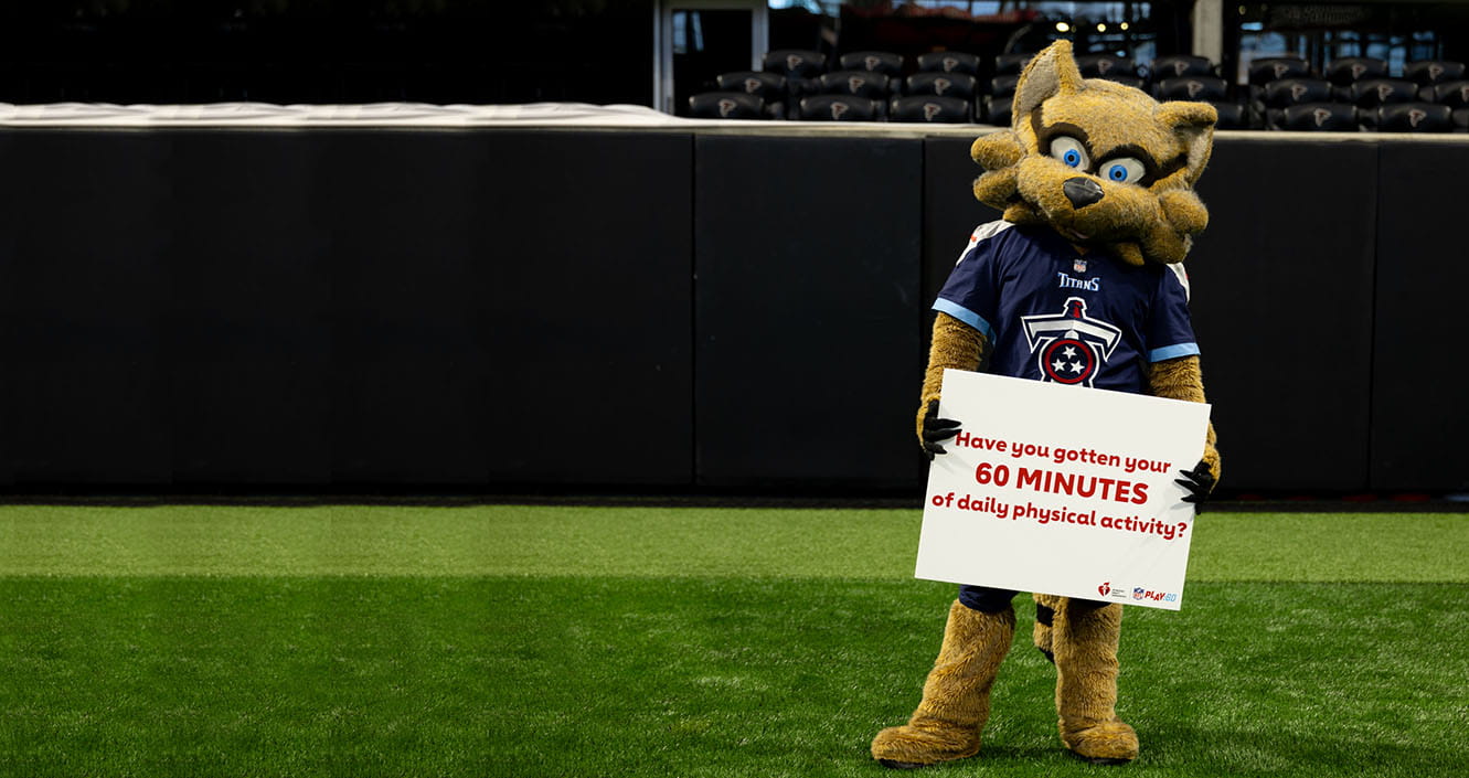 T-Rac, the Tennessee Titans mascot, standing on the field holding a sign that says "Have you gotten your 60 minutes of daily physical activity?"