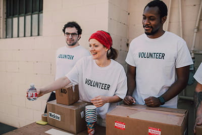 Three college students volunteering and handing out water