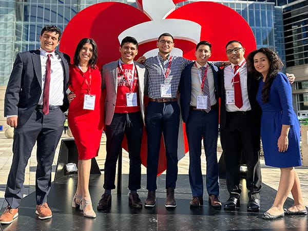 A group of NHLCC scholars standing in front of the AHA's life-size heart and torch sculpture.