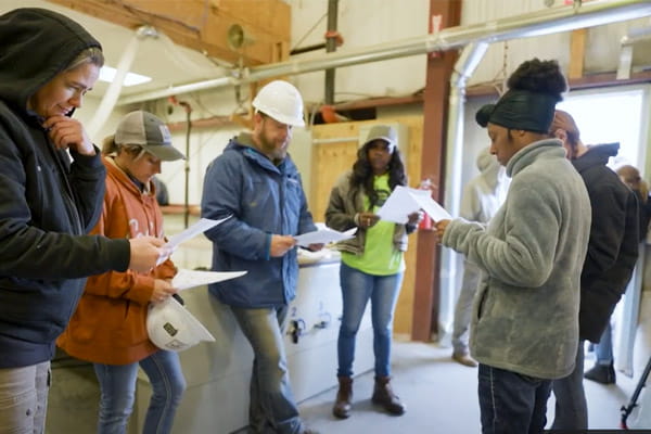 A group of West Virginia Women Work participants are meeting in a warehouse to review a job assignment.